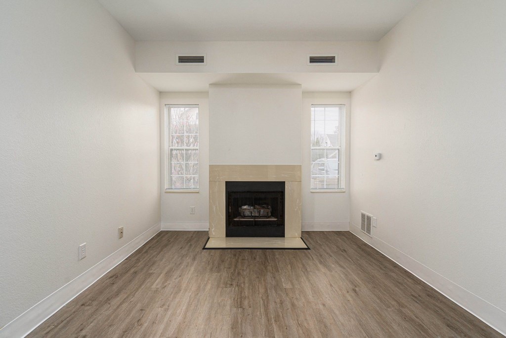 an empty living room with a fireplace and wooden floors